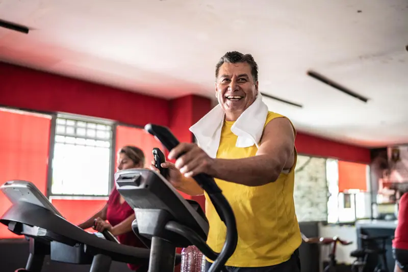 Mantrix Potencia: hombre maduro pedalea con una gran sonrisa en el gimnasio